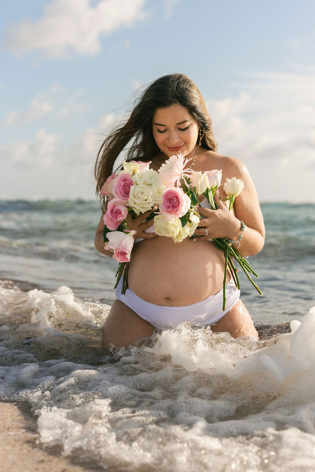 Maternity beach session in Miami with bouquet and ocean waves at sunrise