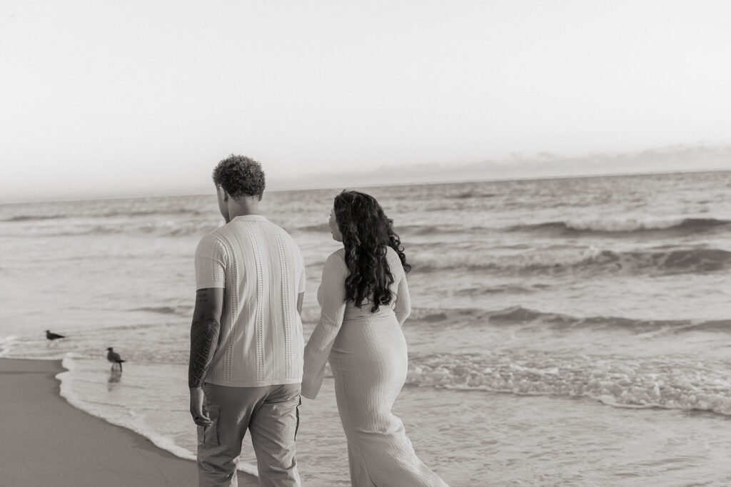 Candid South Florida couple during a maternity photography session walking along the beach.