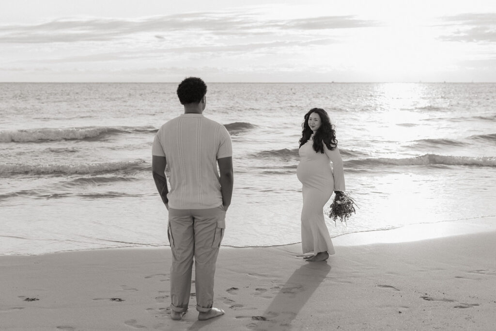 Couple looking at each other during a miami maternity photo session on the beach at sunrise.
