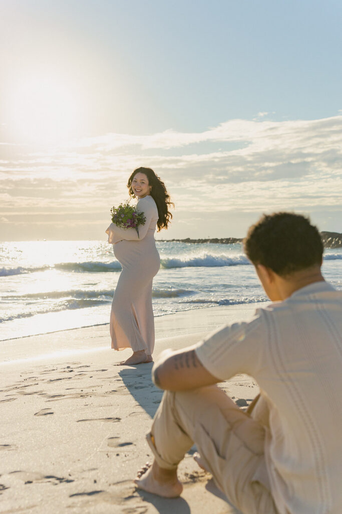 South Florida maternity beach session with expecting mother holding bouquet.