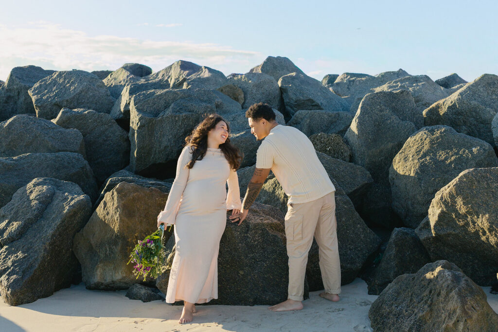 Creative maternity beach photography session in South Florida with coastal rocks.