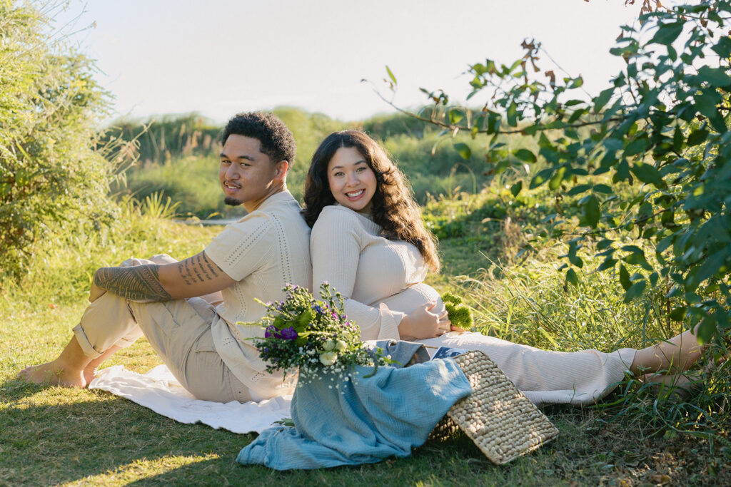 Couple sitting together during a sunset maternity session in a South Florida field.