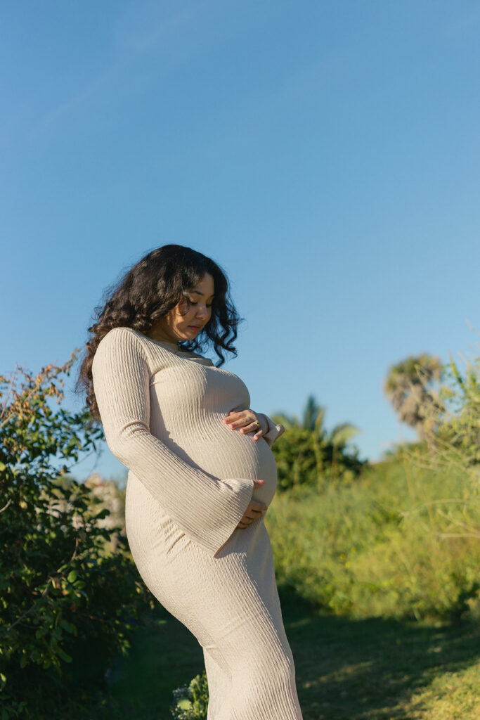 Outdoor maternity photography session in South Florida wild meadow with glowing sunrise light.